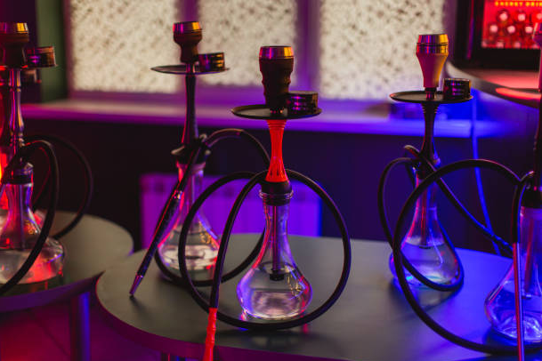 Shishas in a dimly lit lounge with colorful lighting.